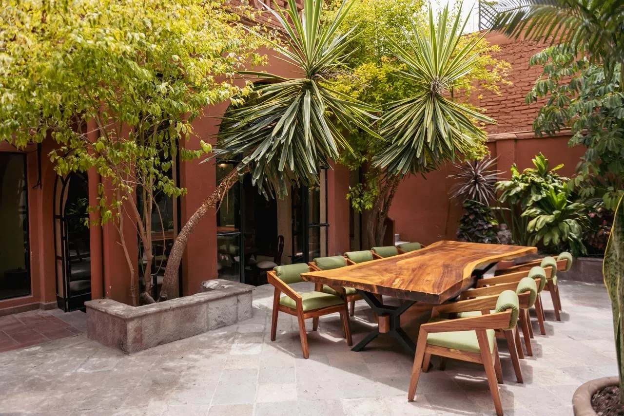 Patio con mesa de madera y palmas, Hotel Xacalli